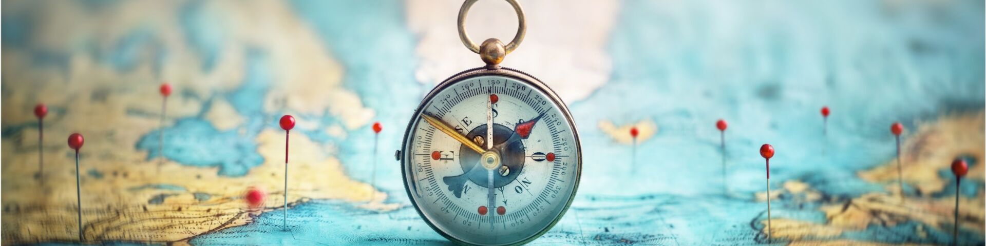 Magnetic compass and location marking with a pin on routes on world map.