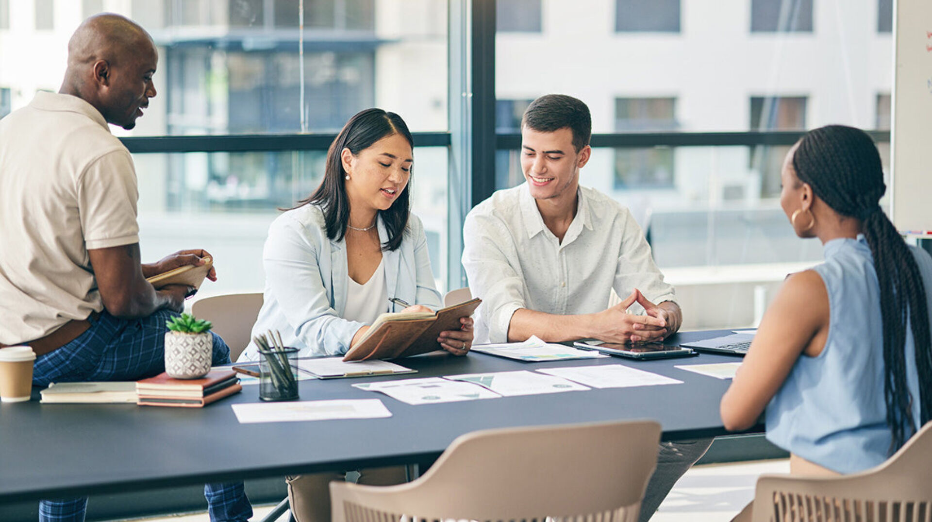 Young, diverse professionals gathered at a table with documents and notebooks.