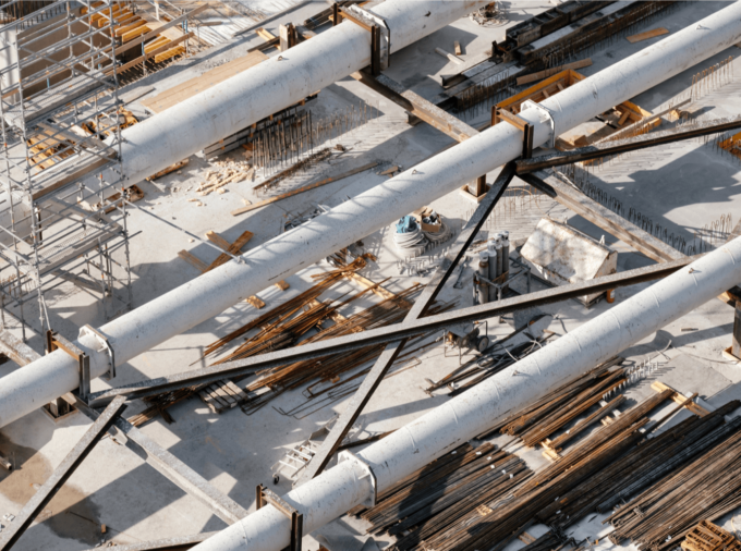 aerial view of three parallel large white pipes on cement ground, with scaffolding and supports.